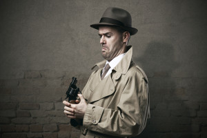 Silly vintage detective pointing a gun to his face and making a dumb expression