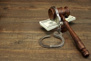 Dollars Cash Real Handcuffs And Judge Gavel On Rough Wood Background. Concept For Arrest Corruption Bail Crime Bribing or Fraud.